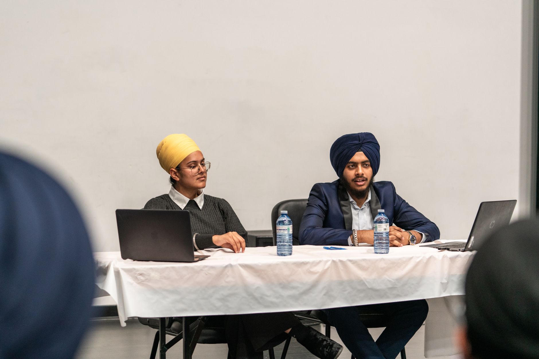 Two Sikh professionals presenting at a conference table, discussing business strategies.