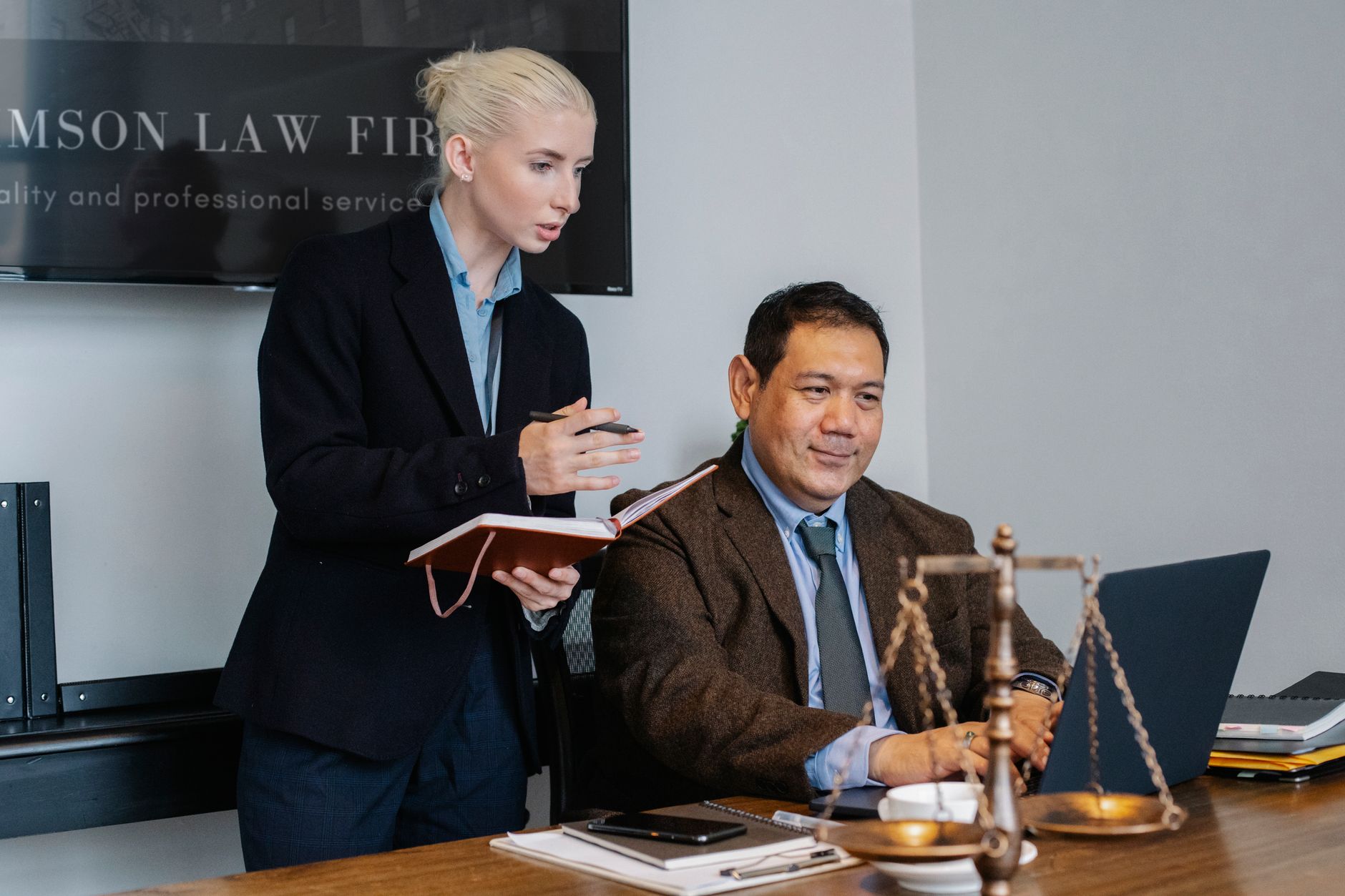 Young female assistant taking notes in planner at meeting