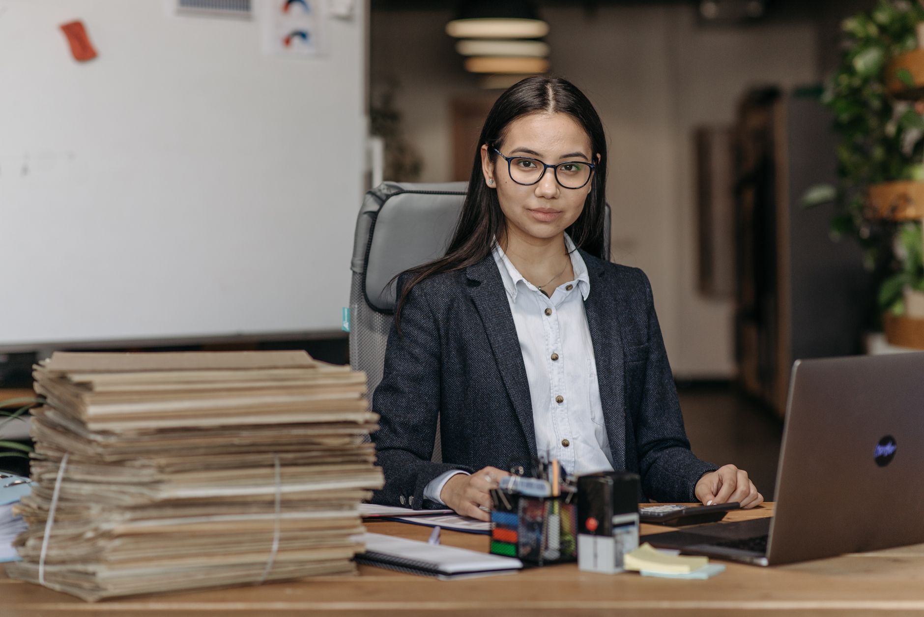 Confident woman with eyeglasses working in a modern office environment.