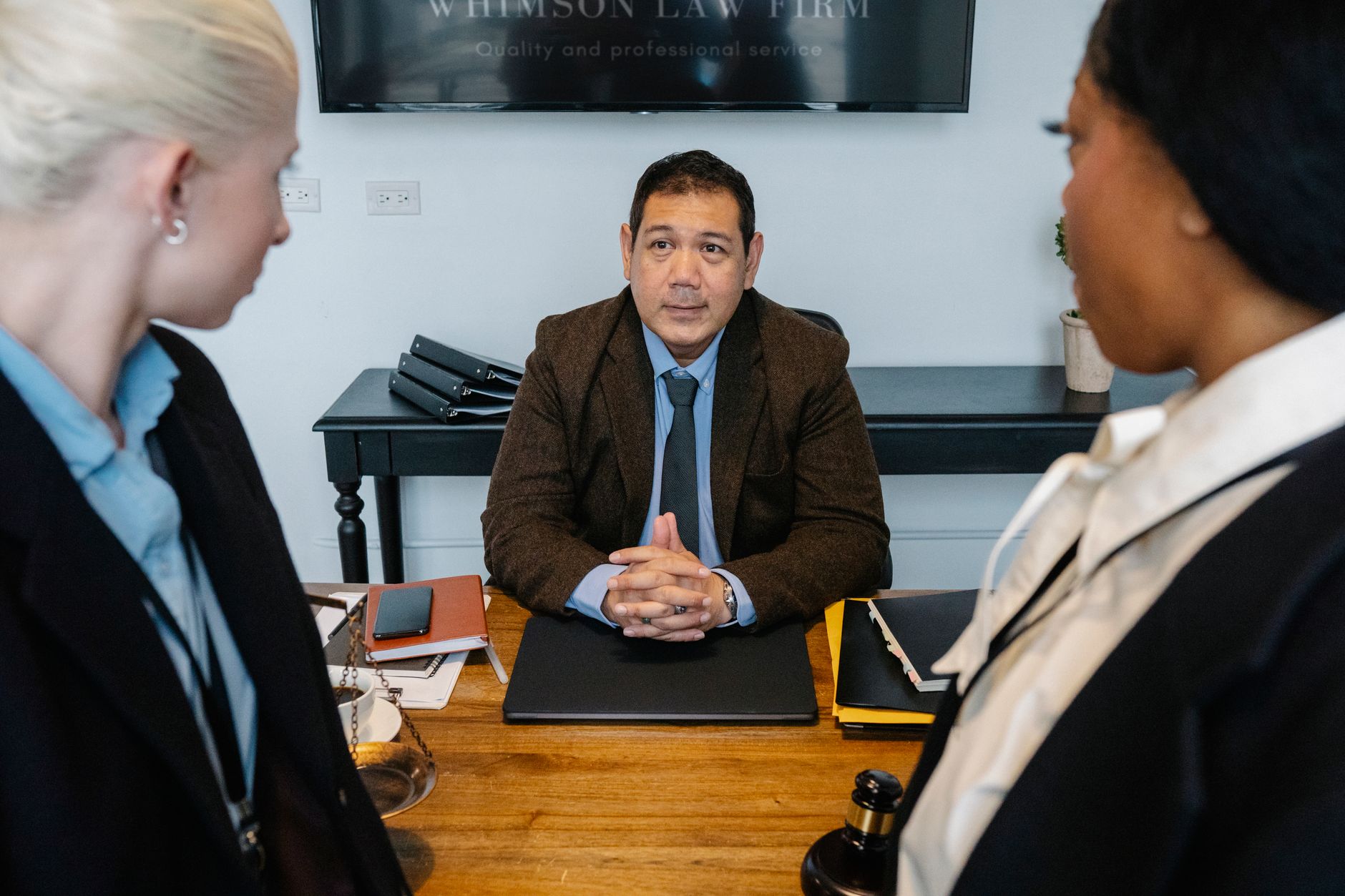 Middle aged ethnic boss discussing strategy with attentive young female colleagues.