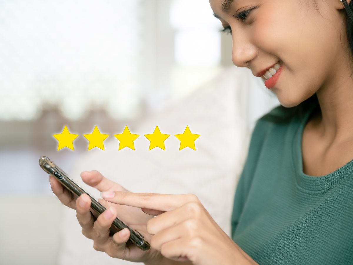 A woman holding a cellphone smiles with 5 star