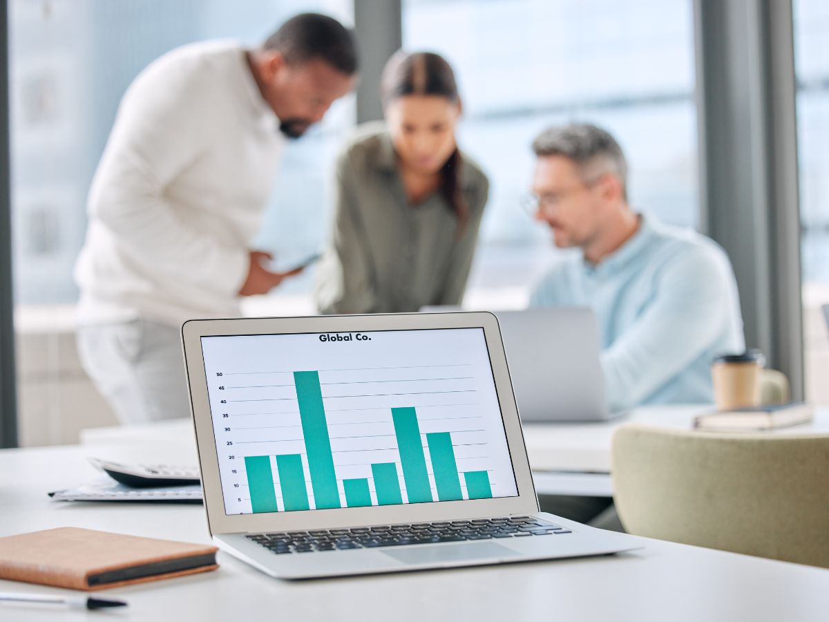 A laptop with a graph and a background of people