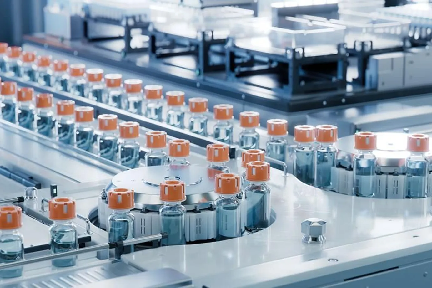 Rows of small glass vials with orange caps on a pharmaceutical production line.