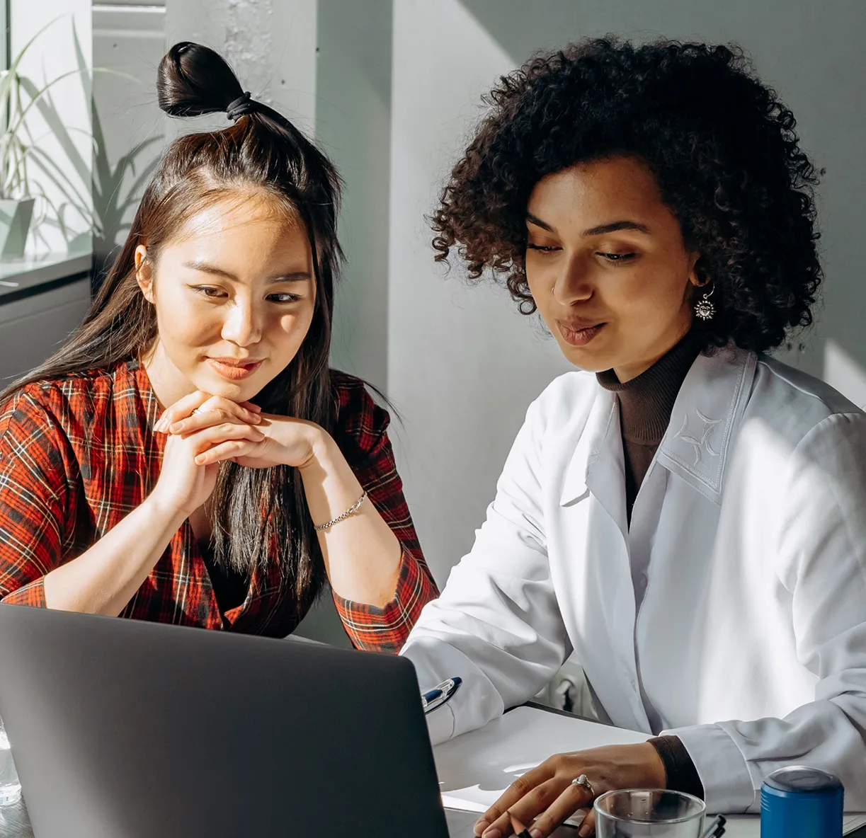 Clinician in a white coat reviewing a personalized treatment plan on a laptop with a young woman.
