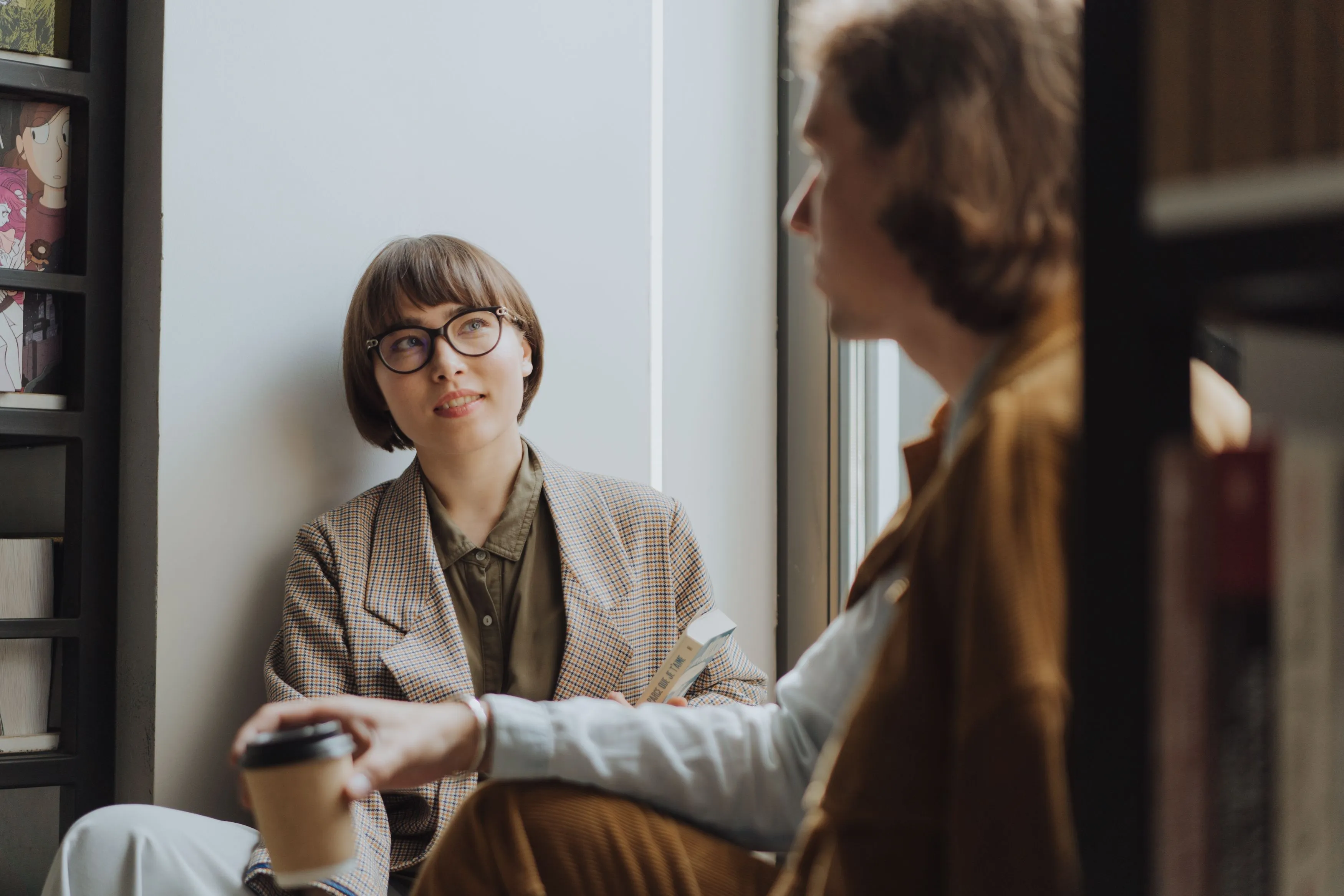 Young woman in glasses listening attentively during a relaxed conversation with a clinician.