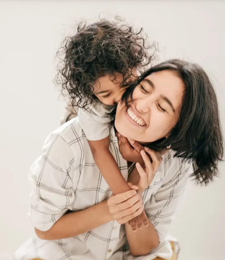 Smiling mother hugging her young child, representing caregivers and families supported by TAC University.