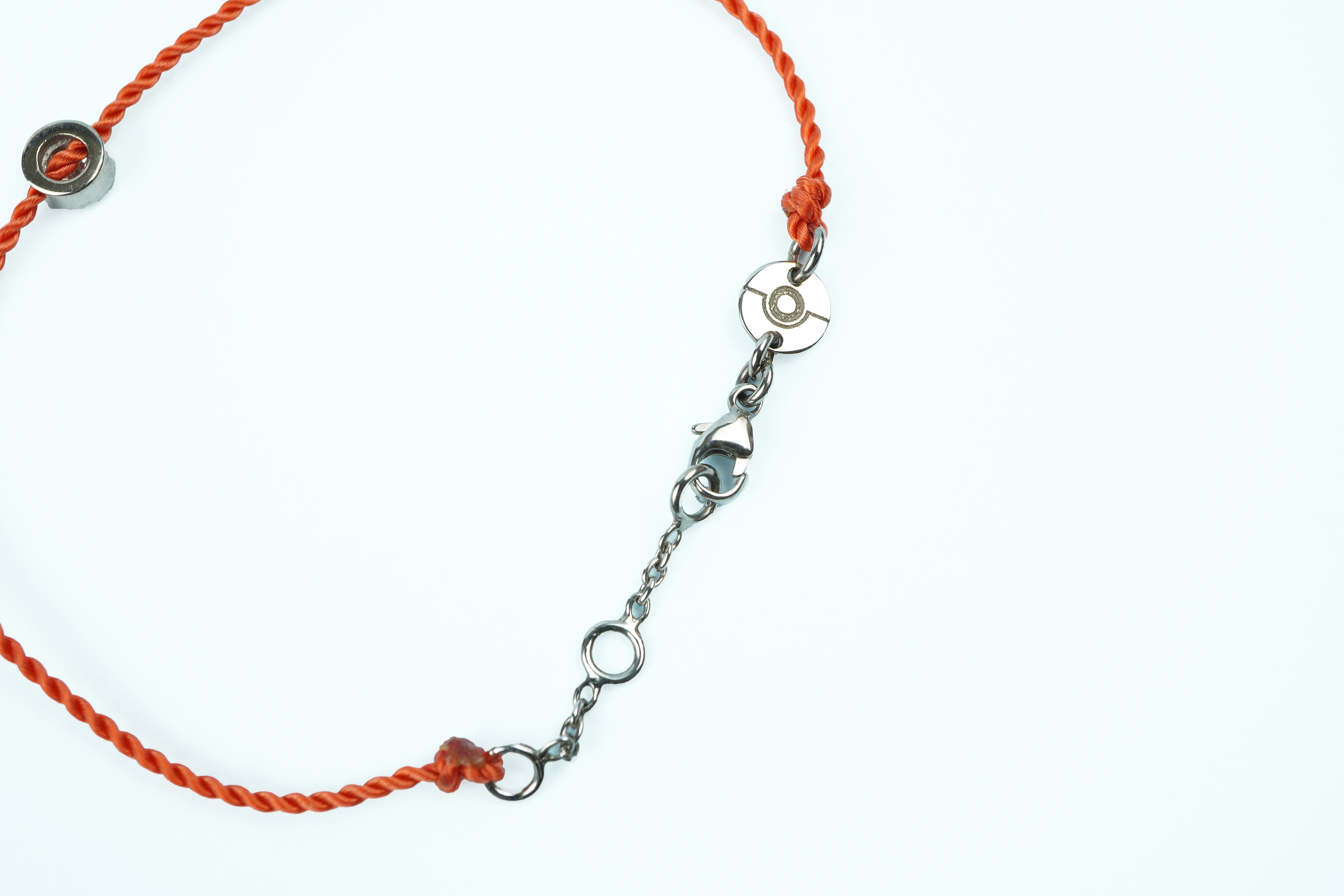 Fermoir du bracelet ONE en or blanc, médaille gravée de l'emblème ONE, cordon orange