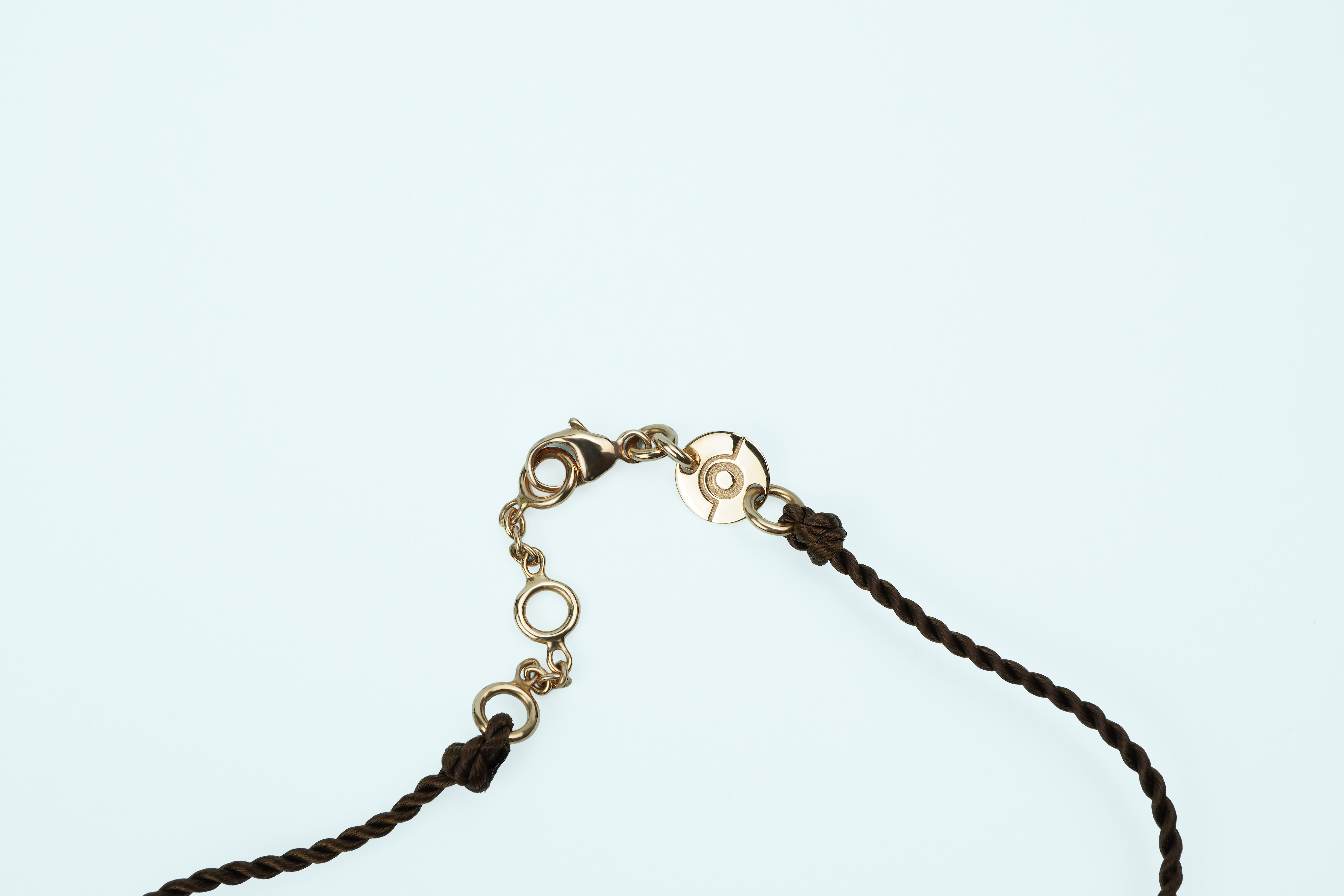 Gros plan sur le diamant serti clos en or rose du bracelet ONE, cordon chocolat