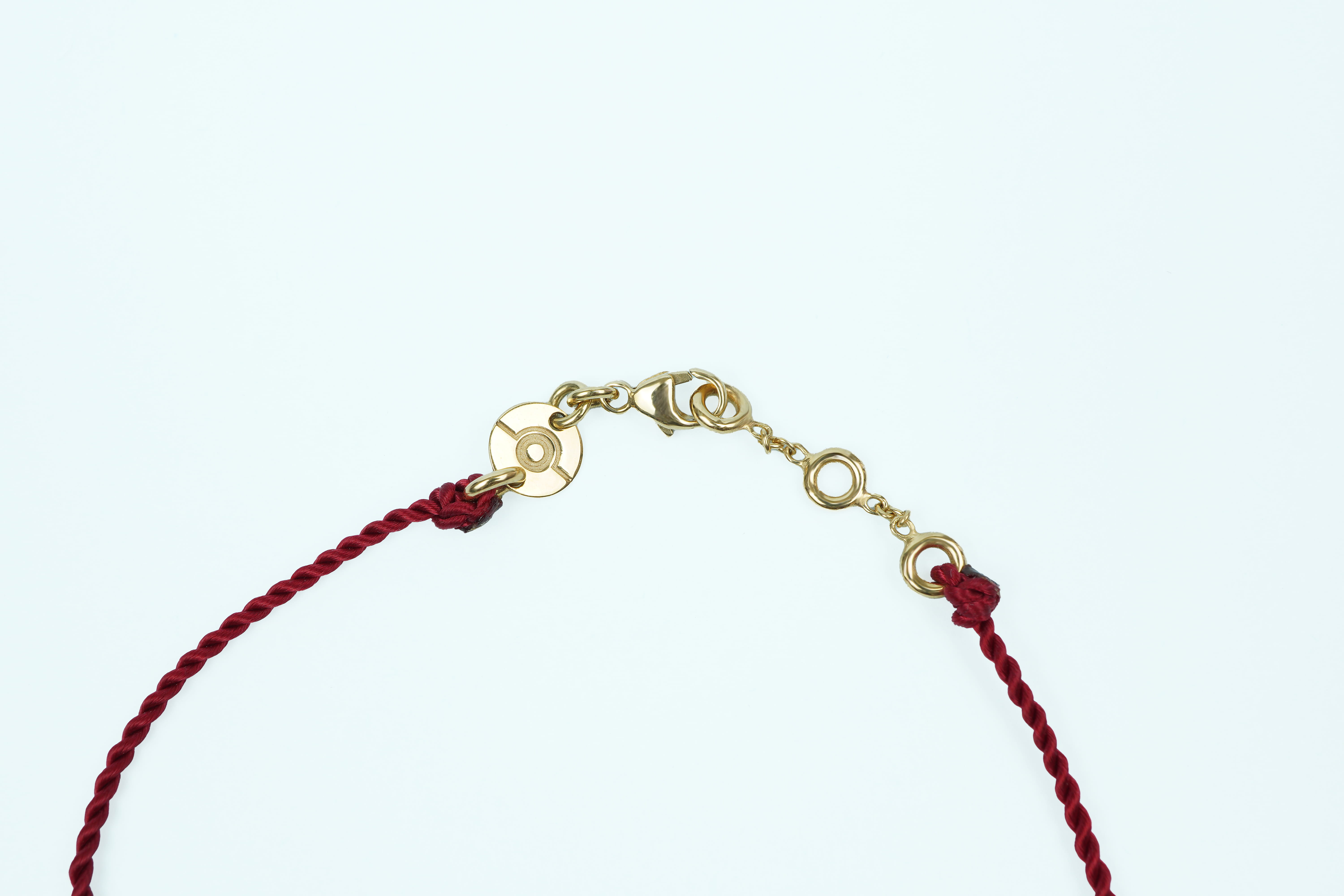 Fermoir du bracelet ONE en or jaune, médaille gravée de l'emblème ONE, cordon bordeaux