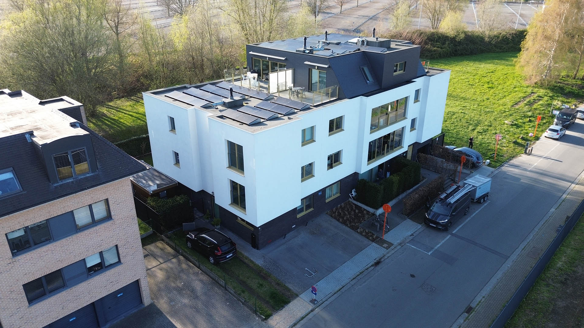 Drone-overzicht van modern appartementsgebouw met zonnepanelen en dakterras tijdens reiniging door Mossmasters