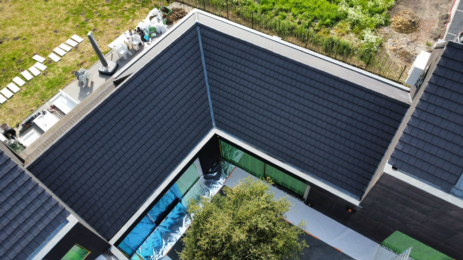 Drone-overzicht van donker leien dak van moderne woning met binnenplaats tijdens dakreiniging door Mossmasters