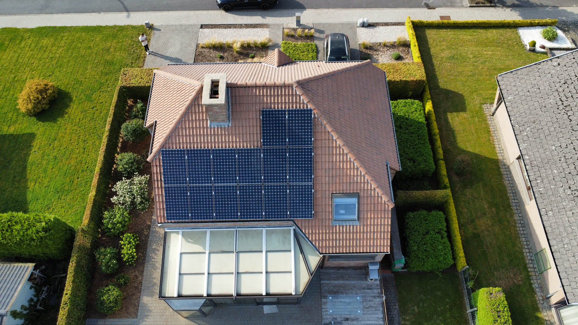 Drone-overzicht van gereinigd pannendak met zonnepanelen en glazen veranda na behandeling door Mossmasters