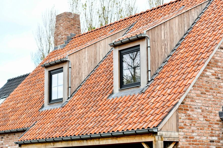 Gereinigd oranje pannendak met houten dakkapellen en bakstenen gevel na dakreiniging door Mossmasters