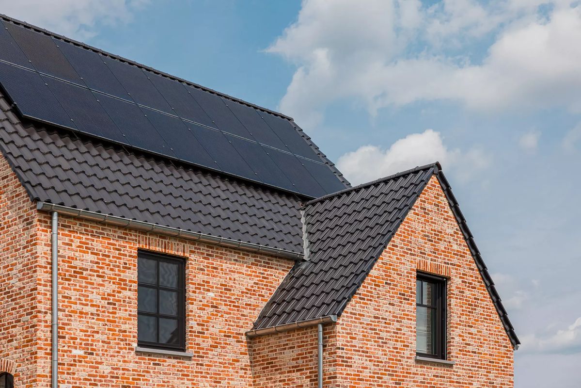 Gereinigd donker pannendak met zonnepanelen op bakstenen woning na dakreiniging door Mossmasters