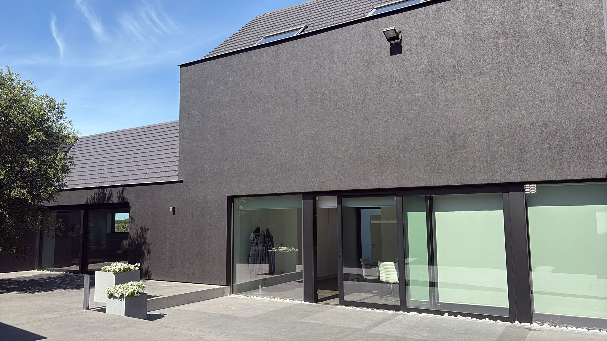 Gereinigde donkere gevel en leien dak van moderne architectuurwoning met terras na behandeling door Mossmasters