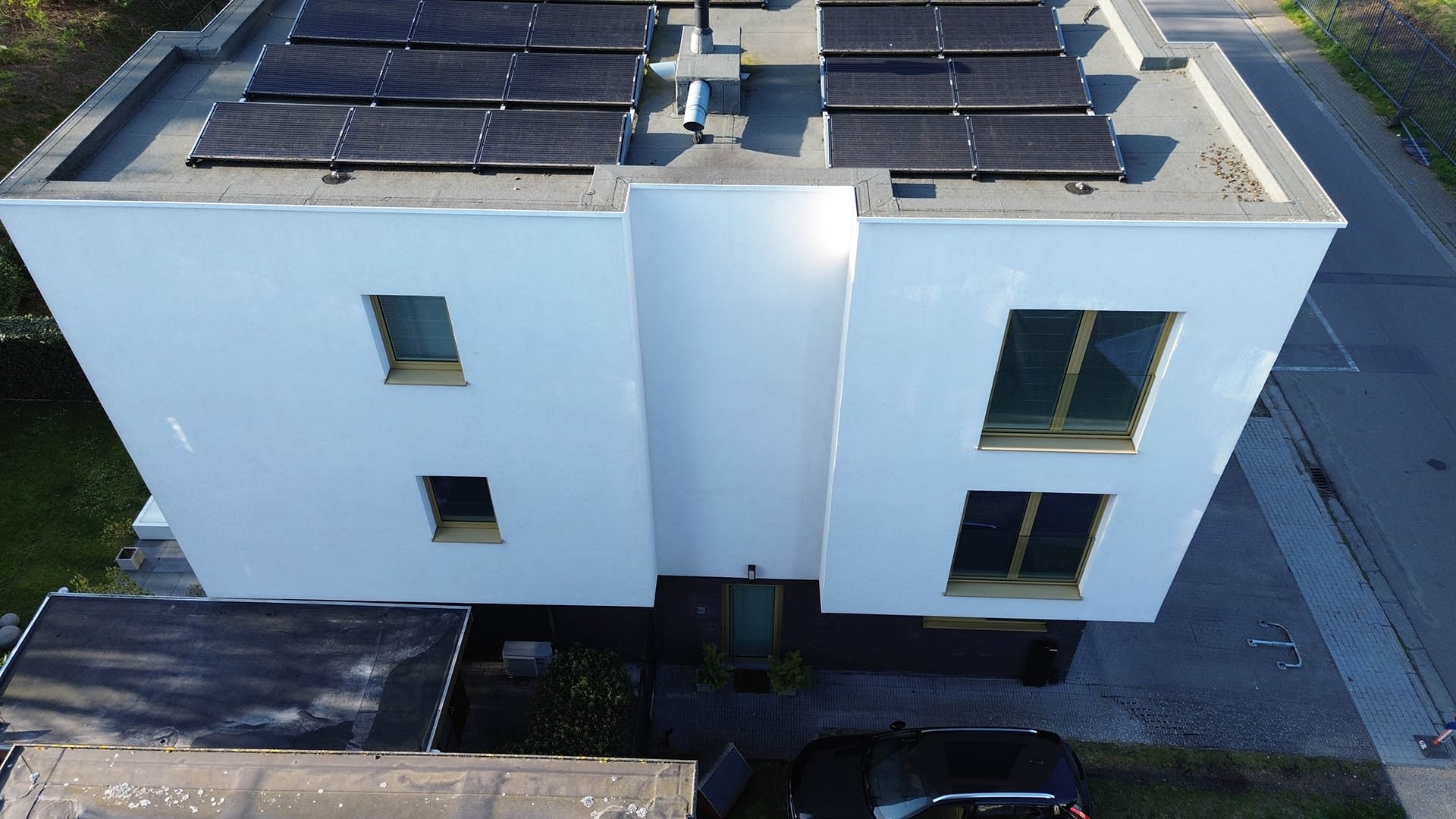 Drone-overzicht van modern wit gebouw met plat dak vol zonnepanelen na reiniging door Mossmasters