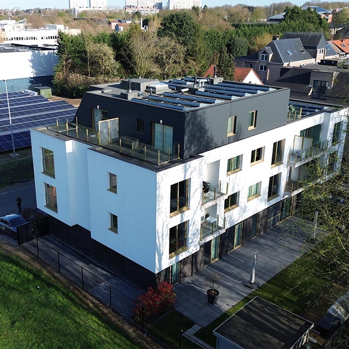 Drone-overzicht van modern appartementsgebouw met plat dak en zonnepanelen na reiniging door Mossmasters