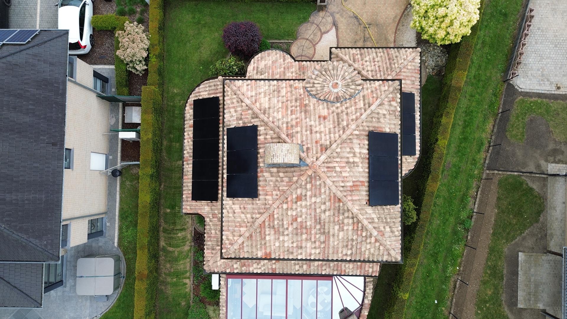 Drone-overzicht van Mediterraan pannendak met zonnepanelen en glazen veranda na dakreiniging door Mossmasters