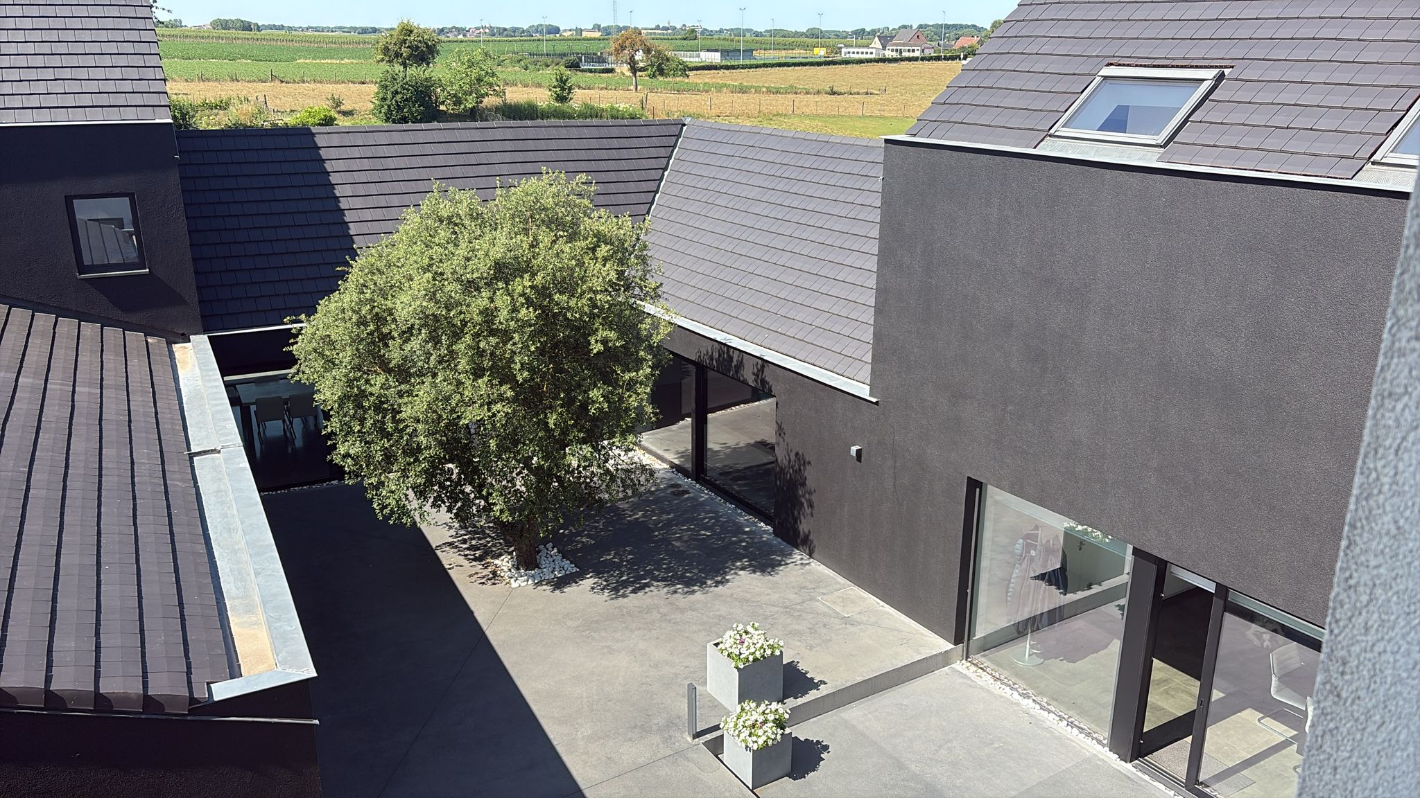 Gereinigd leien dak en grijze gevels van moderne architectuurwoning met binnenplaats behandeling door Mossmasters