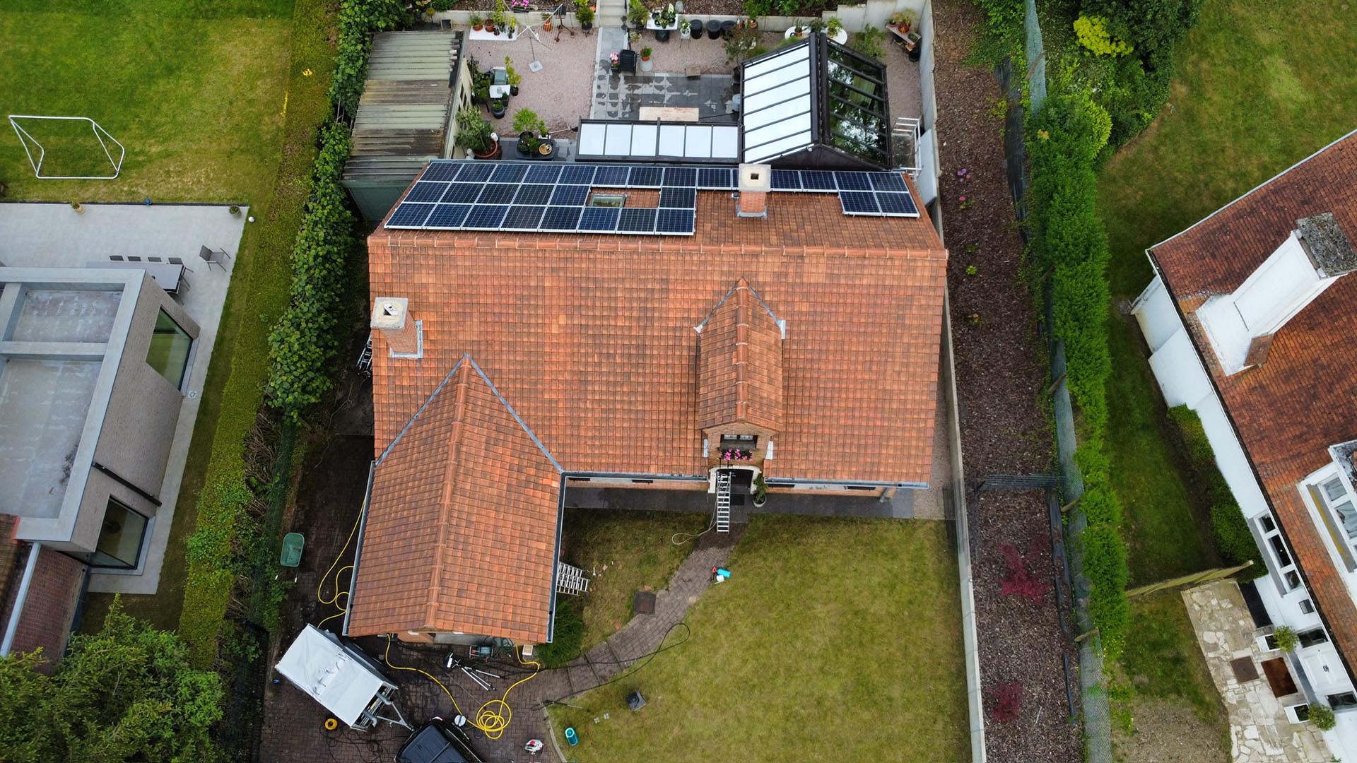 Drone-overzicht van pannendak met grote installatie zonnepanelen tijdens dakreiniging door Mossmasters