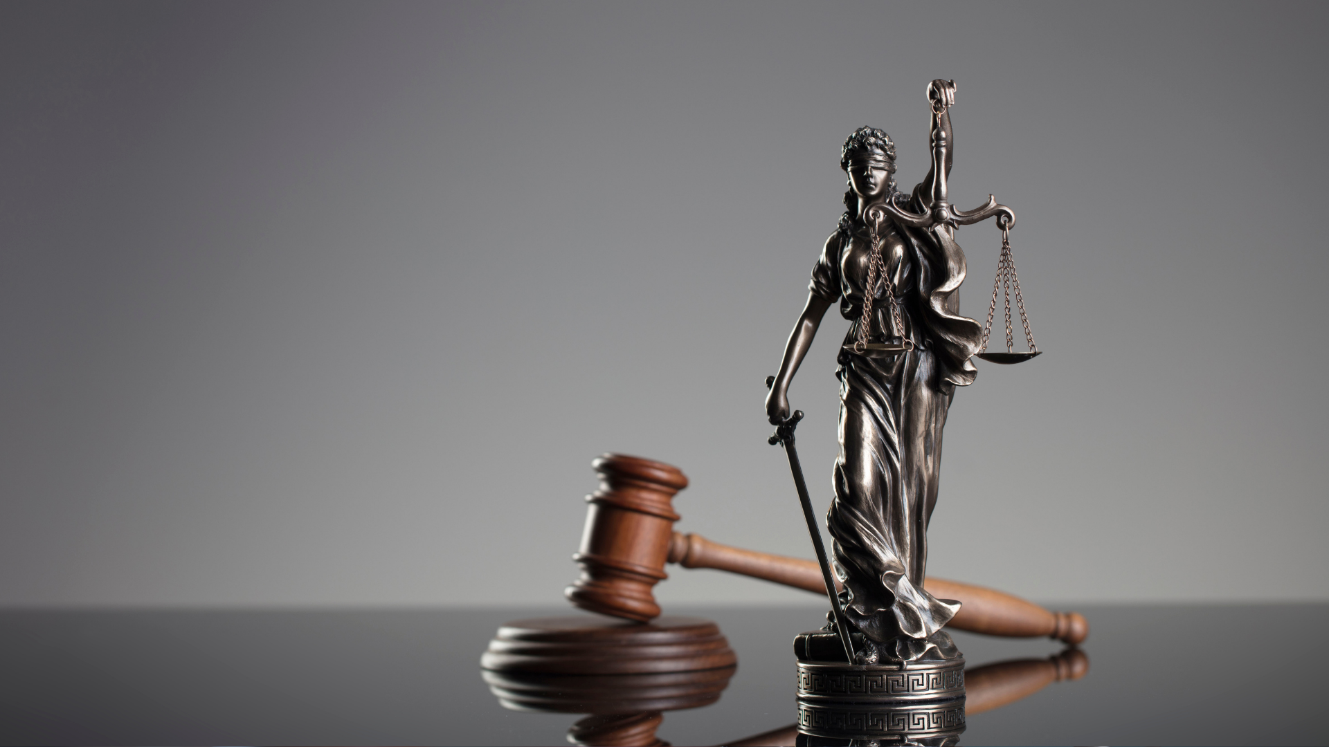 Kleine Justizia-Figur aus Messing und einen Richter-Hammer auf einem Tisch