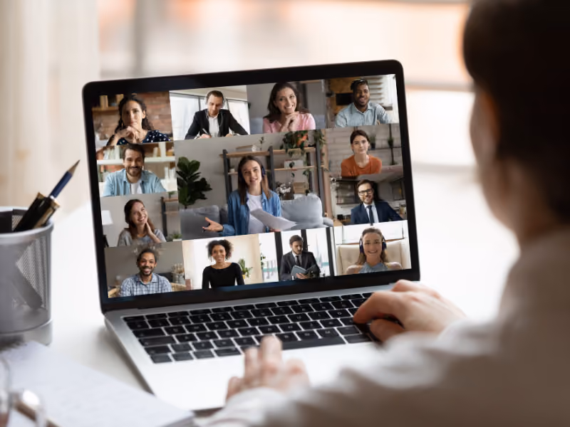 Person sitzt vor einem Laptop und nimmt an einem Online-Meeting teil