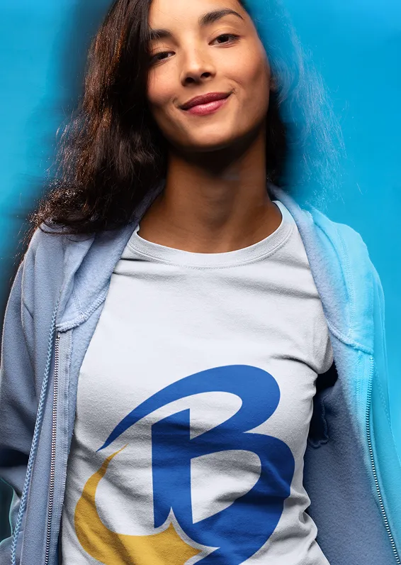 Smiling woman with curly hair wearing a white T-shirt with a blue and yellow logo on a blue background.
