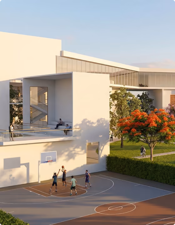 People playing basketball on outdoor court near modern white building with trees and green lawn.