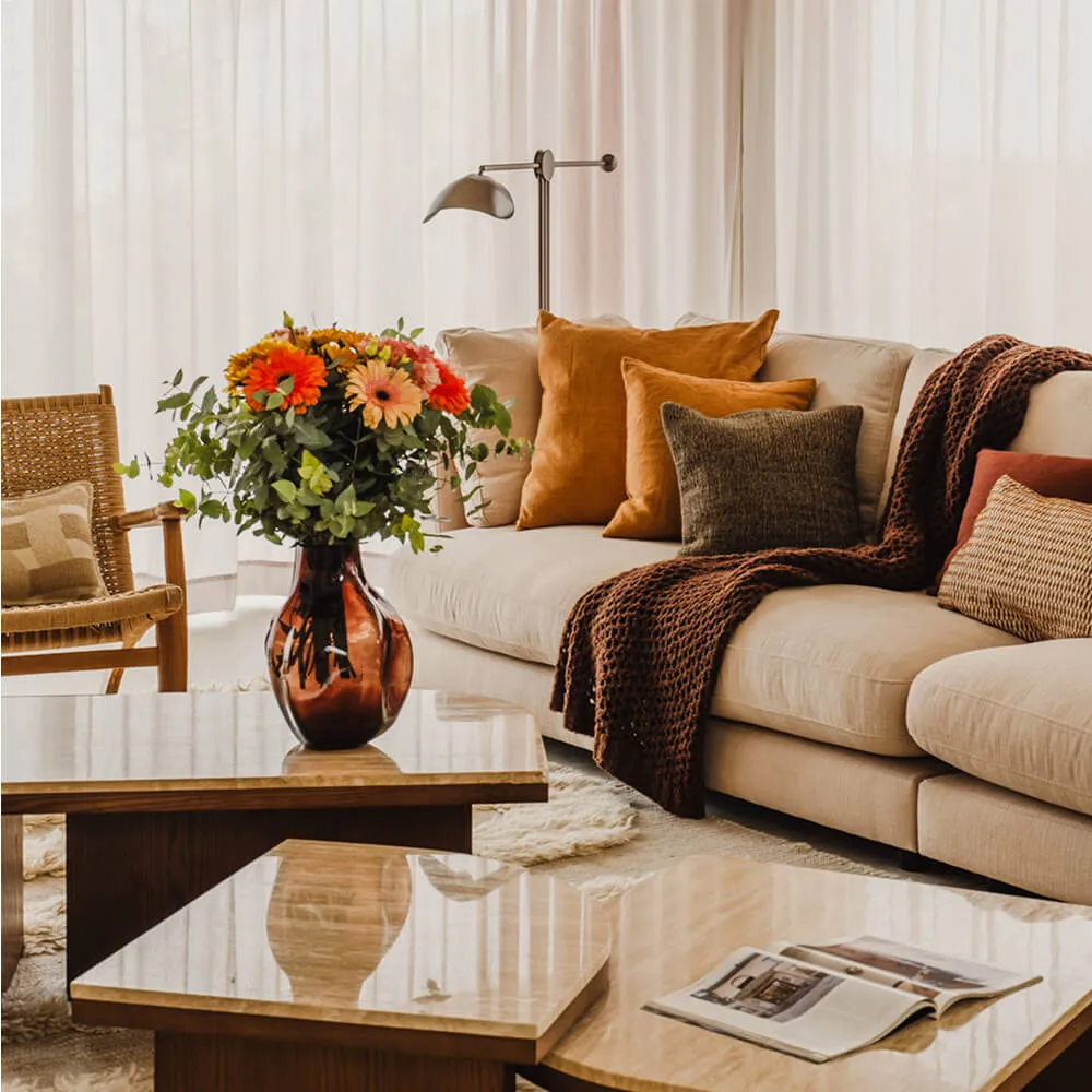 Luxury living room interior design at the Villa Serenity residential project in Ibiza by Studio Moravová, featuring a cream modular sofa, warm earth-toned pillows, and polished travertine coffee tables.