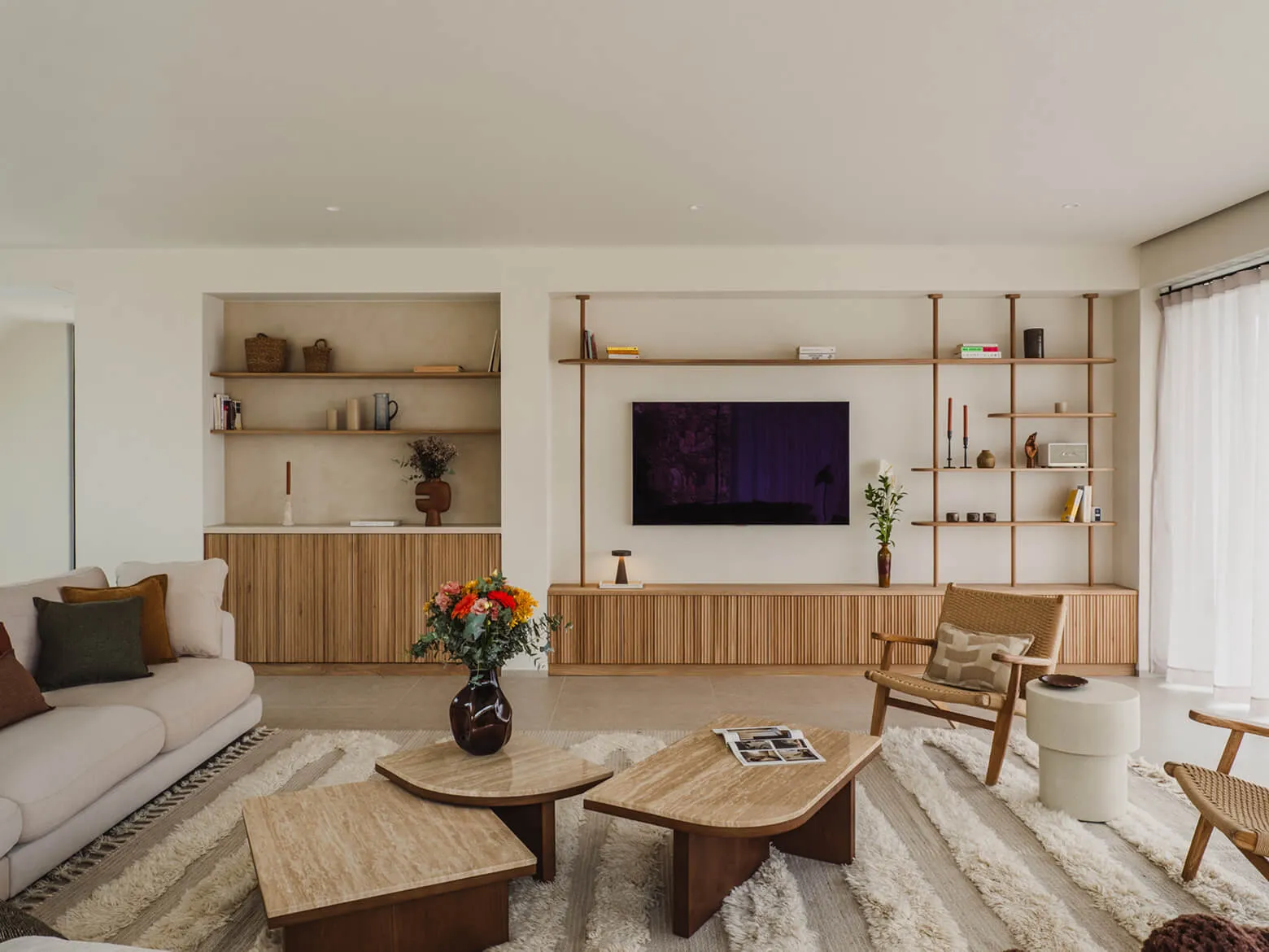 Arquitectura interior minimalista en Ibiza en Villa Benimussa, que destaca los gabinetes de madera estriada personalizados, las estanterías abiertas integradas y un diseño moderno de pared multimedia.