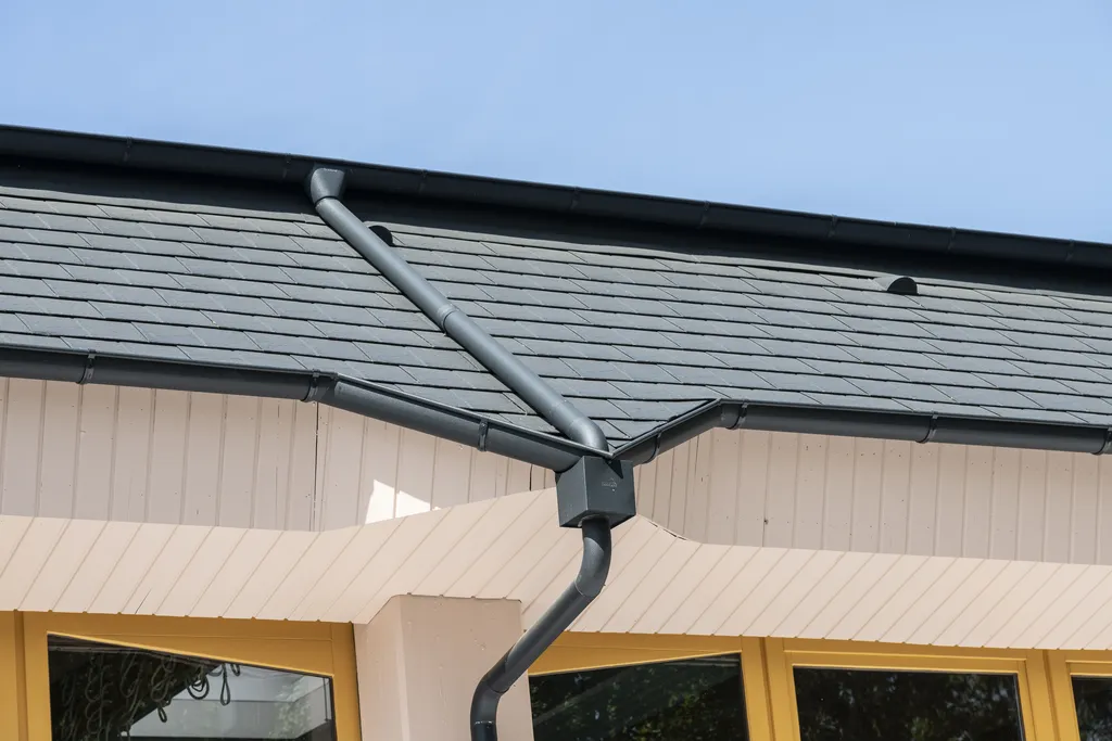 Dachtraufe mit aluminiumschindeln und fallrohr