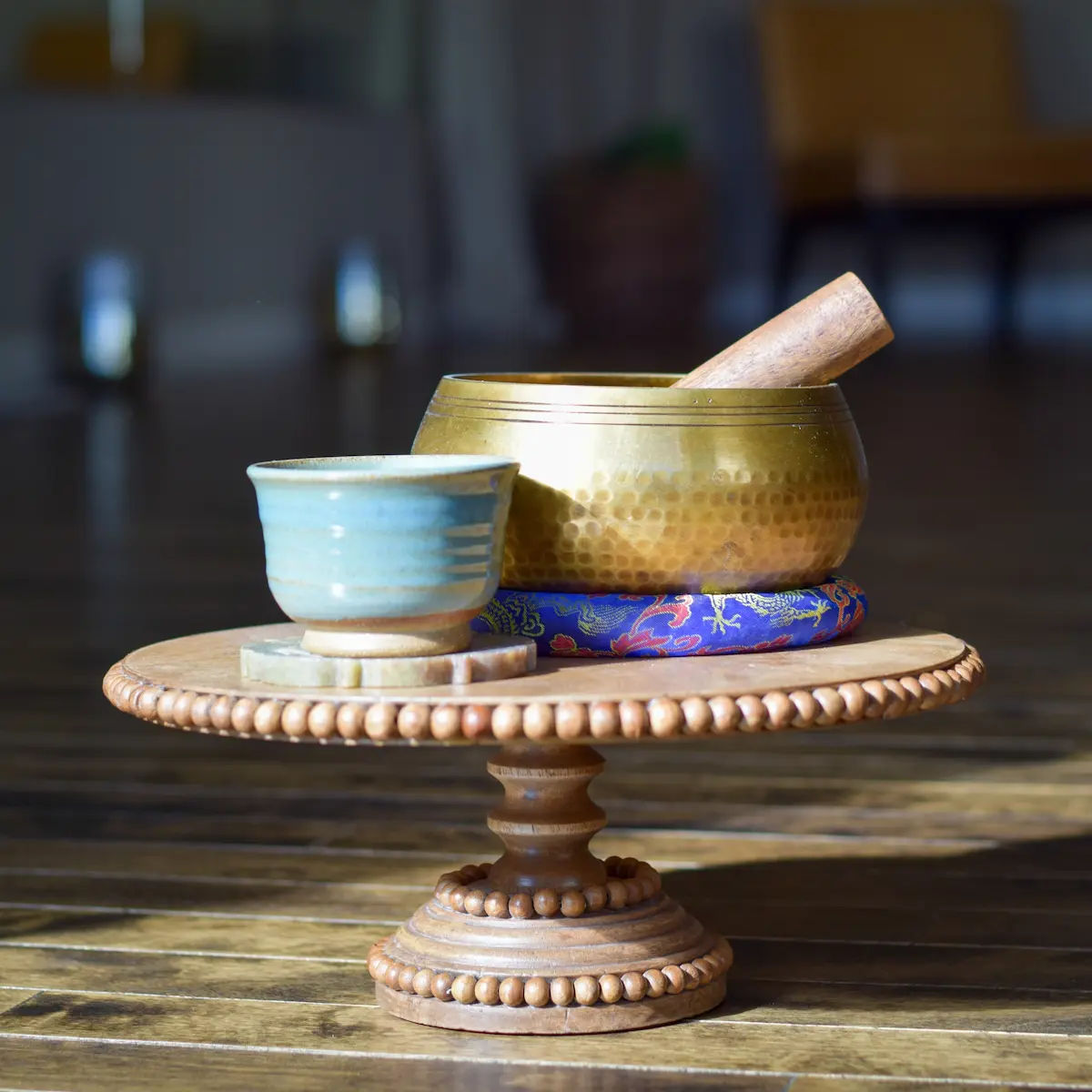 Table with singing bowl and pottery on a clay stand