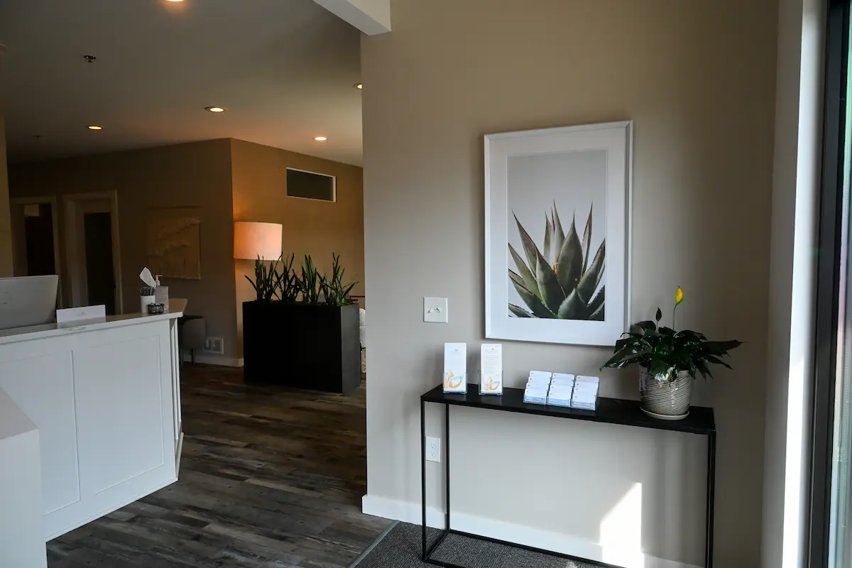 Plymouth office entryway with desk, console table, and paintings