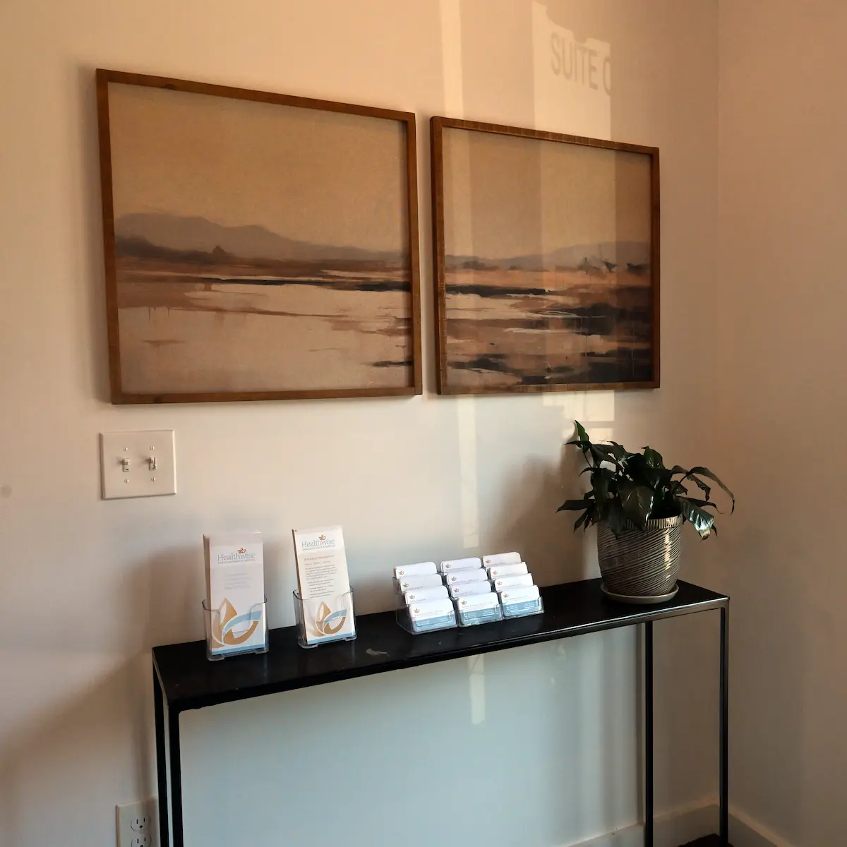 Entryway of Plymouth office with console table and paintings on the wall above