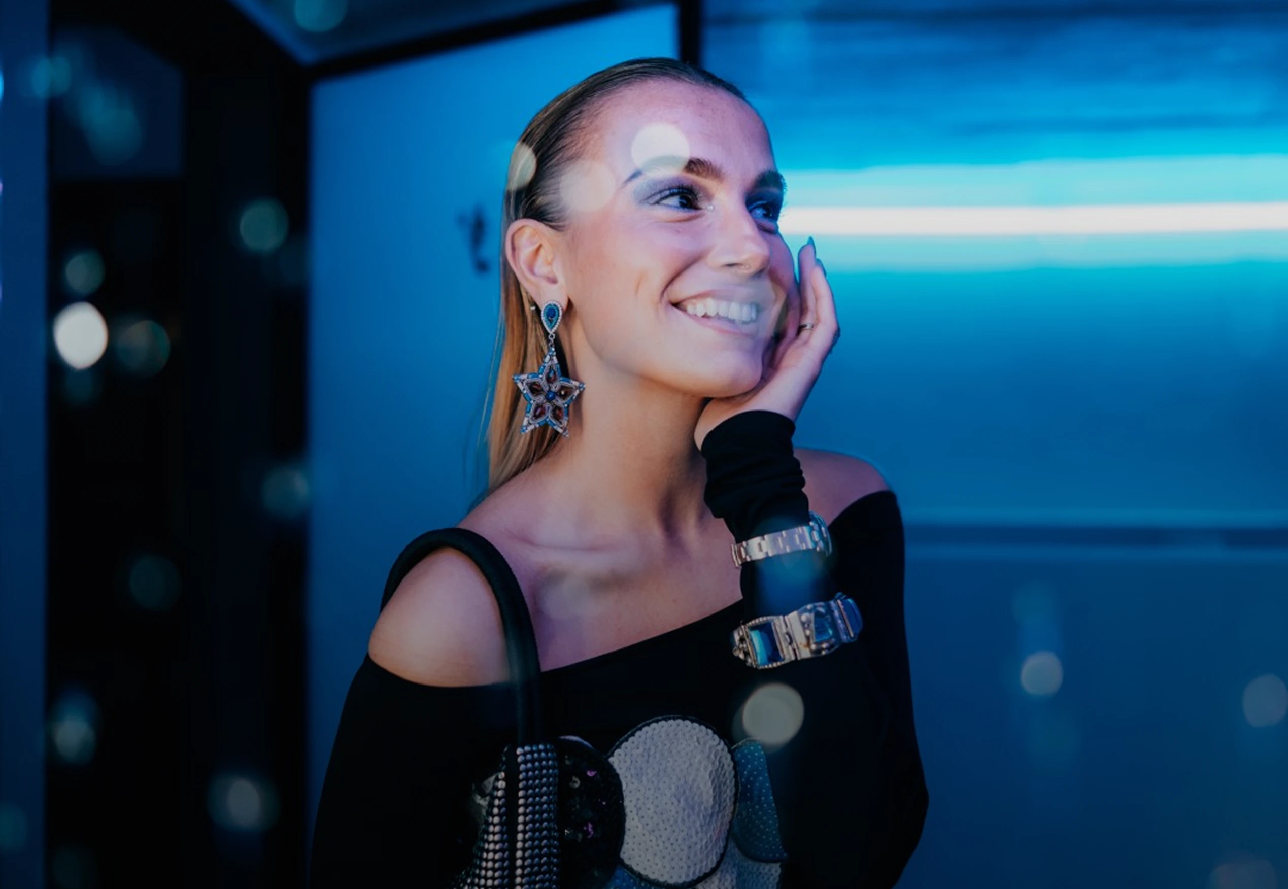 Guest in evening wear laughing under blue neon lighting at a How It Is event