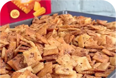 Tray filled with seasoned, square cracker snacks with visible seasoning and spice flakes.