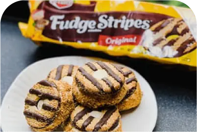 White plate with several Fudge Stripes Original cookies with chocolate stripes on top.