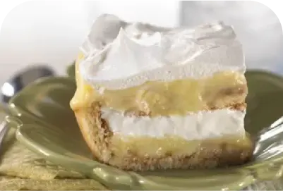 Slice of banana pudding pie with layered filling and whipped topping on a green plate.