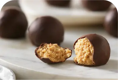 Chocolate-covered truffles with one cut open showing a textured creamy peanut butter filling.