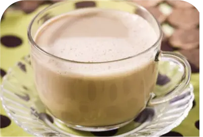 Clear glass cup of frothy latte on a glass saucer with a polka dot tablecloth background.