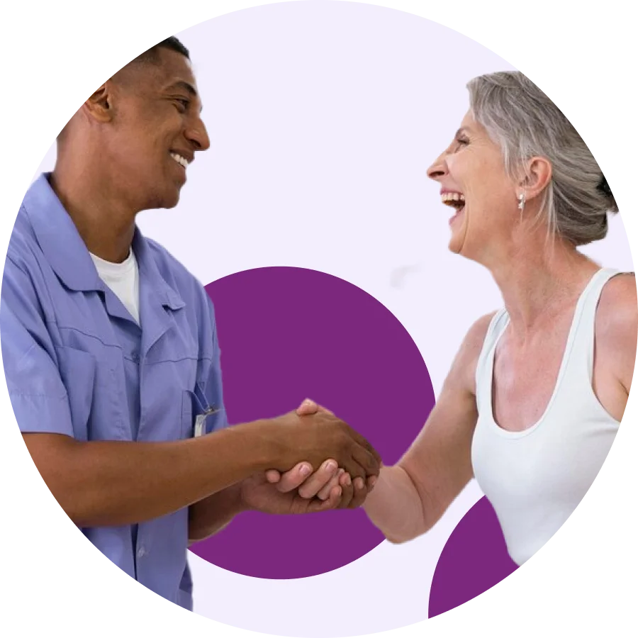 Physical therapist in scrubs shaking hands with a smiling older patient