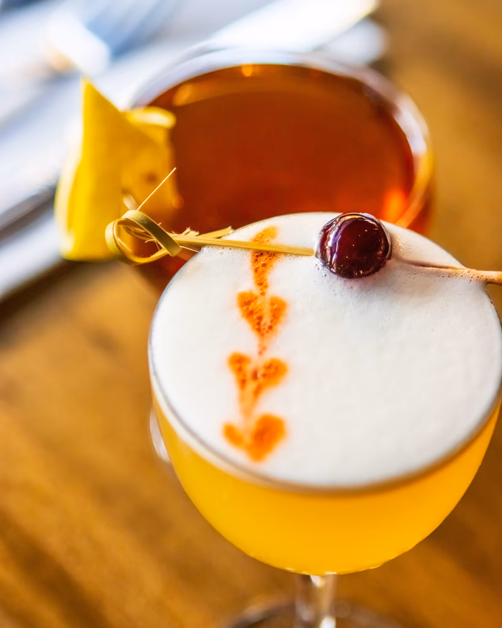 A glass of alcohol with a lemon wedge in it.