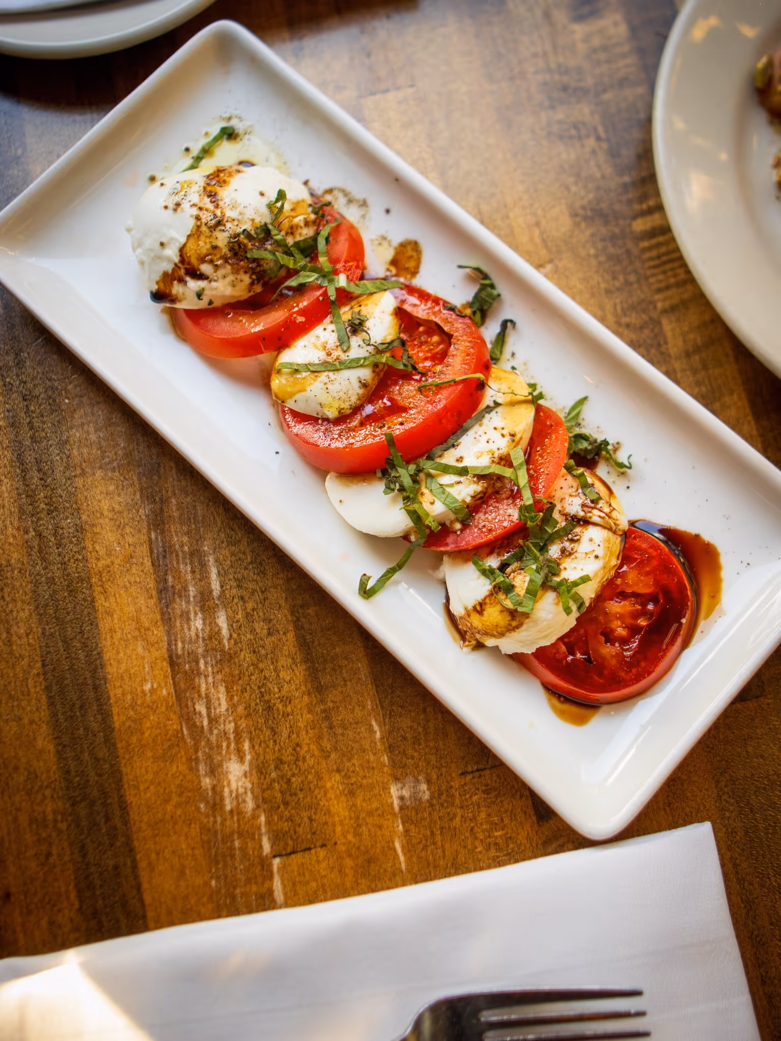 A white plate with tomatoes and cheese on it.