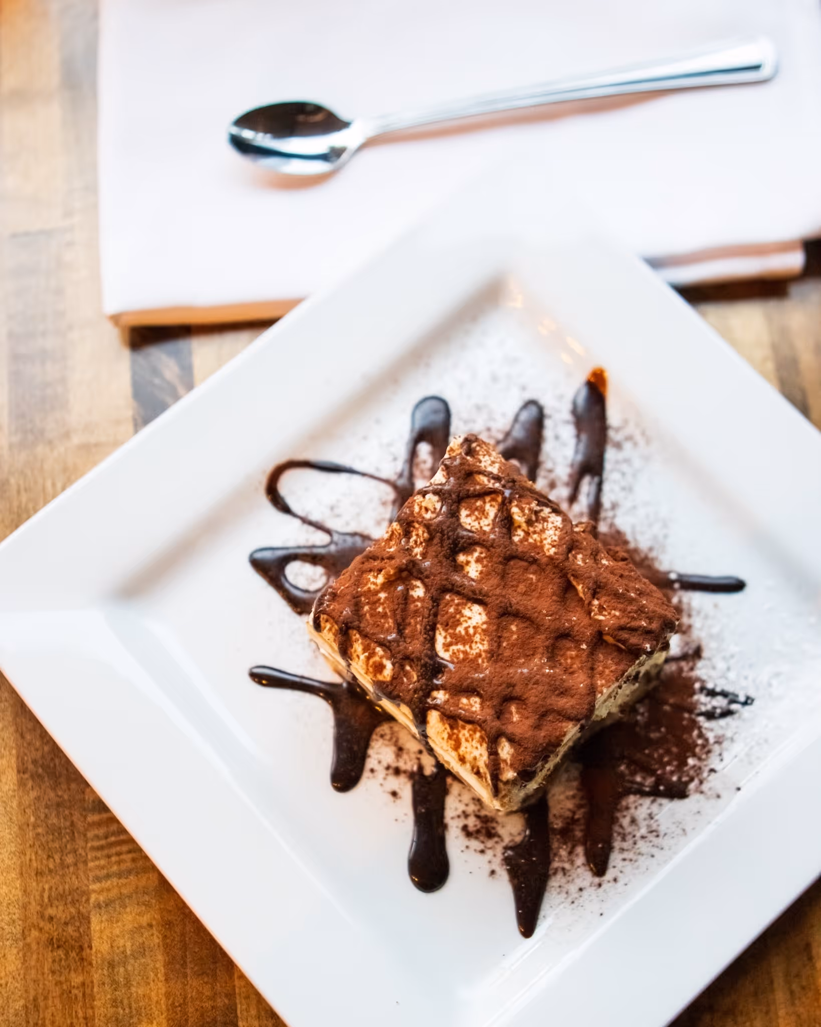 A white plate with a piece of chocolate cake on it.