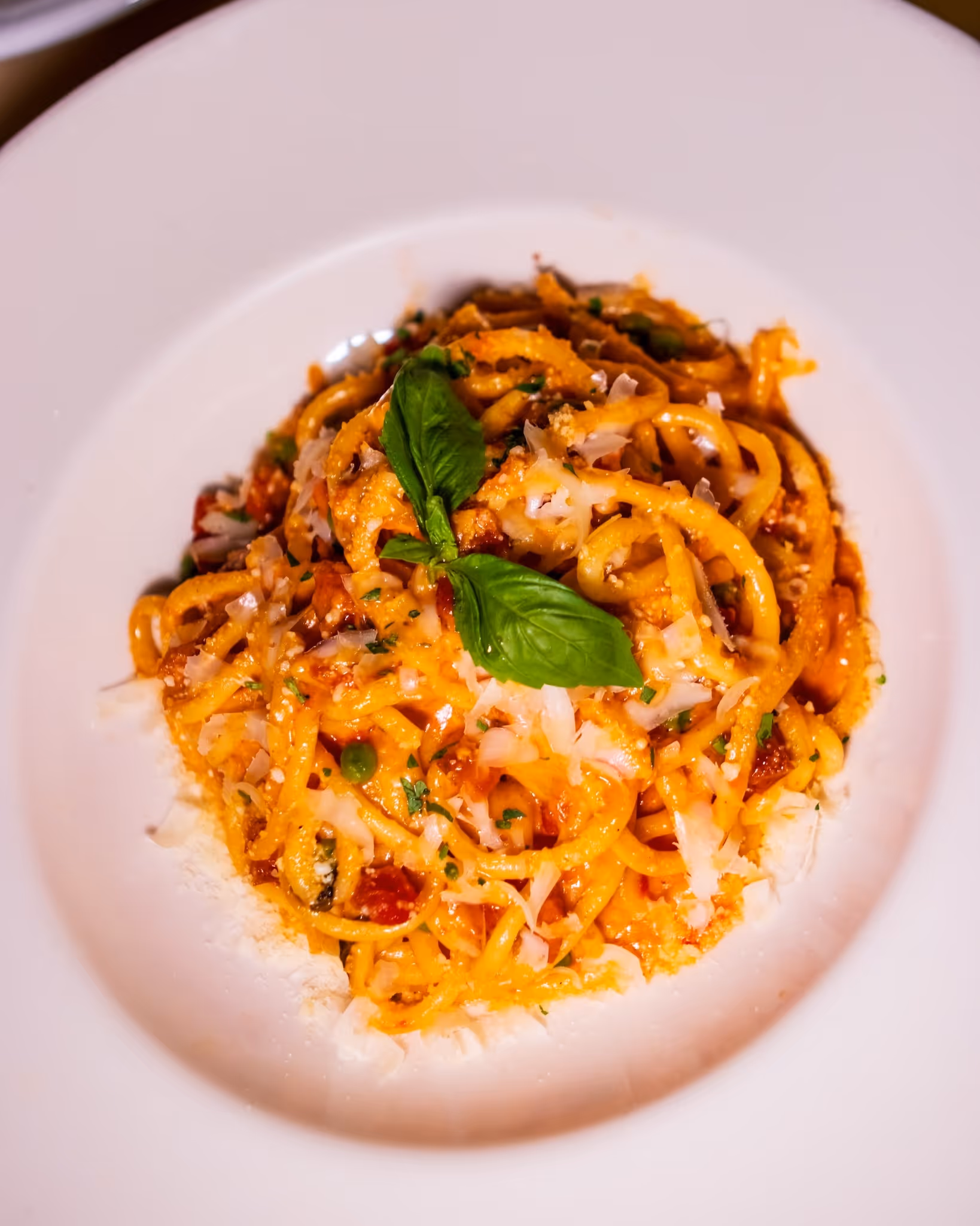 A plate of spaghetti with meat sauce and green leaves.