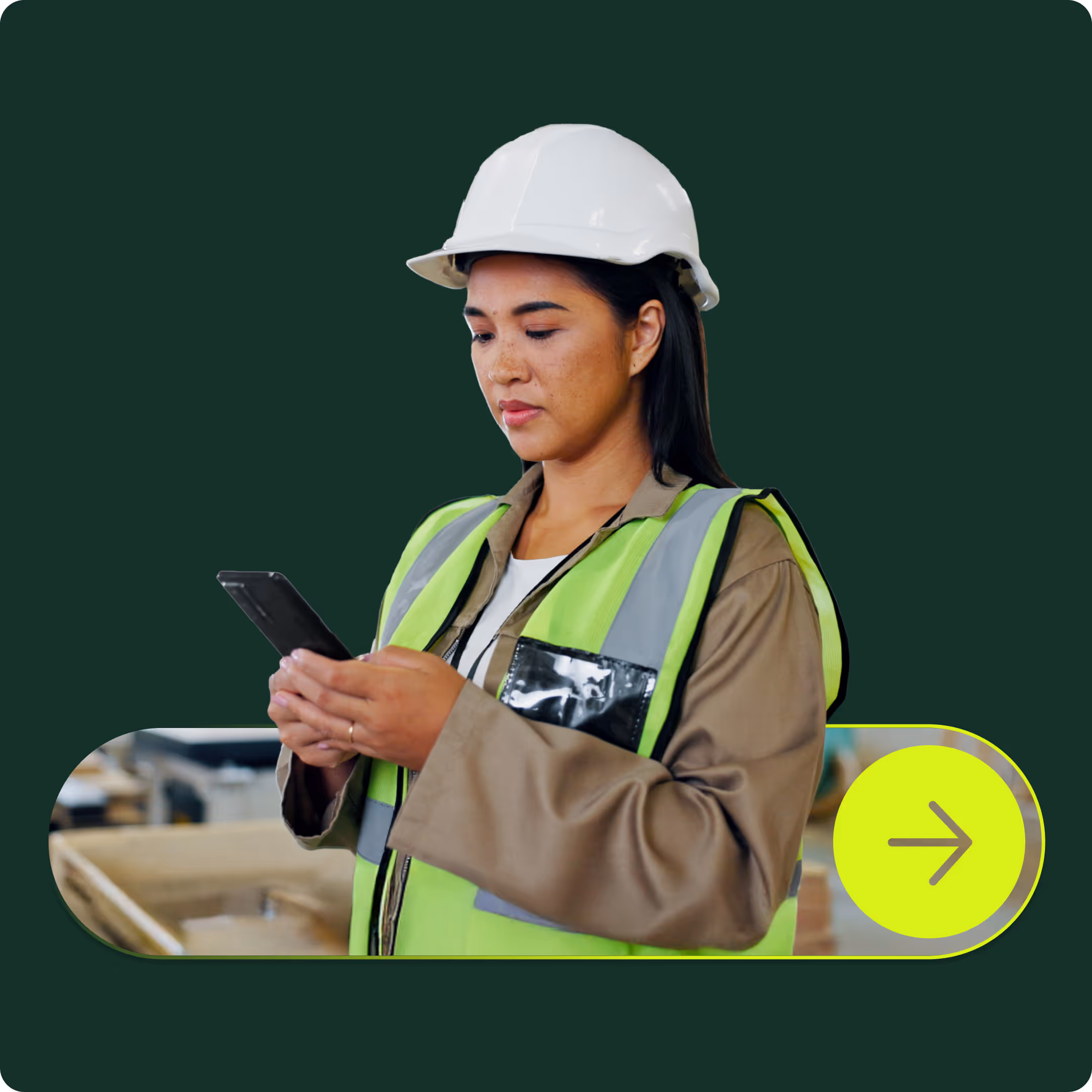 Female construction worker wearing a hard hat and safety vest looking at a smartphone.