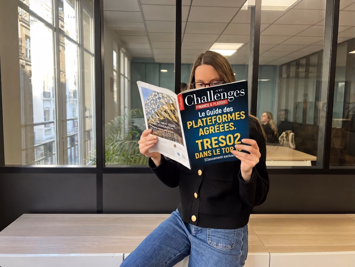 femme-assise-sur-un-bureau-avec-magazine-Challenge-dans-les-mains-sur-classement-10-meilleures-plateformes-agreees