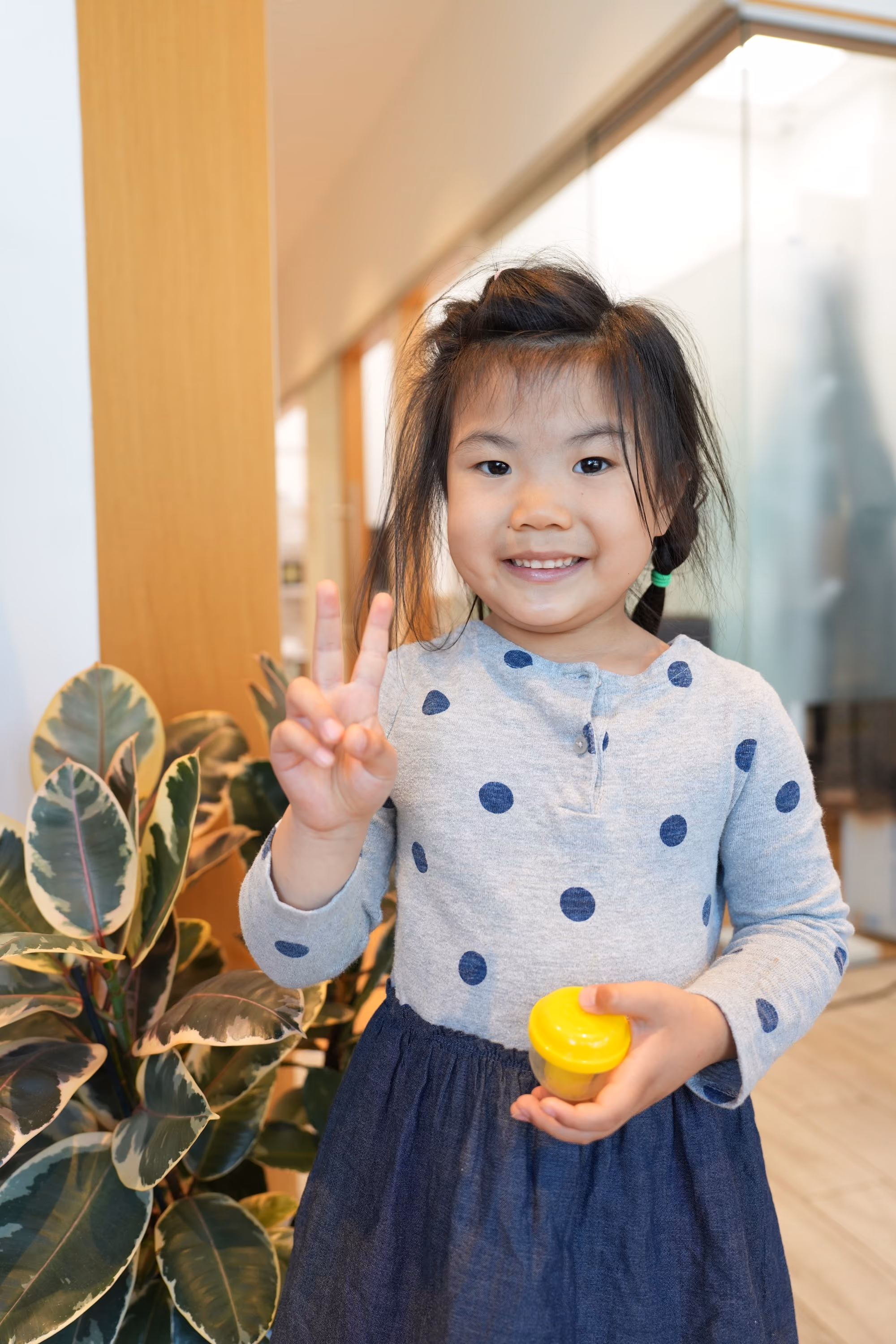 Smiling girl holding a prize capsule after her checkup at DTC Dental Treatment Center in Richmond, BC