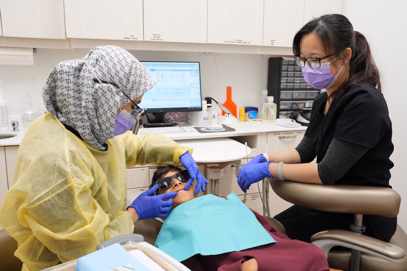 Dentist and dental assistant treating a young patient wearing protective glasses at DTC Dental Treatment Center in Richmond, BC