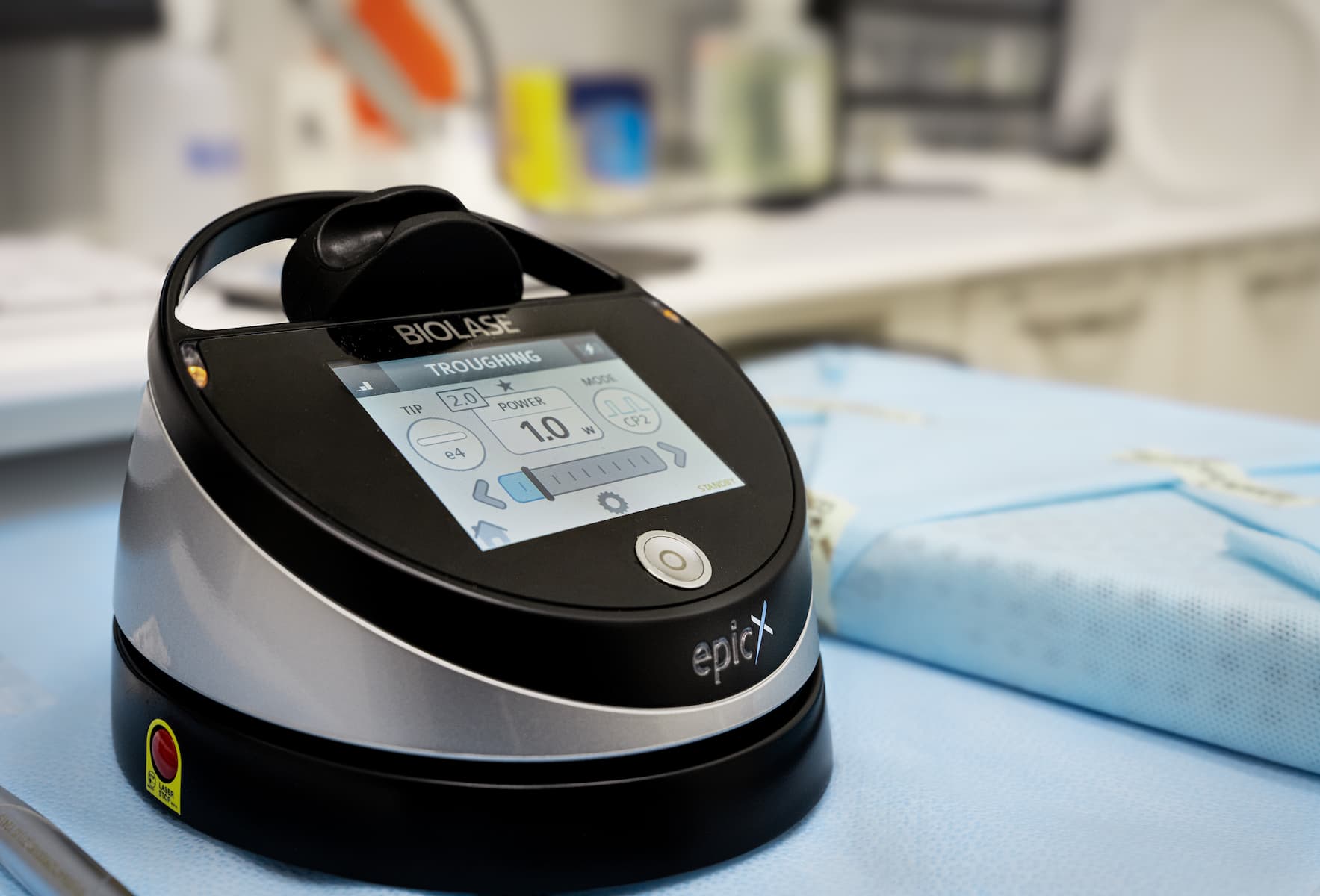Close-up of a BiOLASE dental laser device, the epicX, on a sterile blue cloth, illustrating